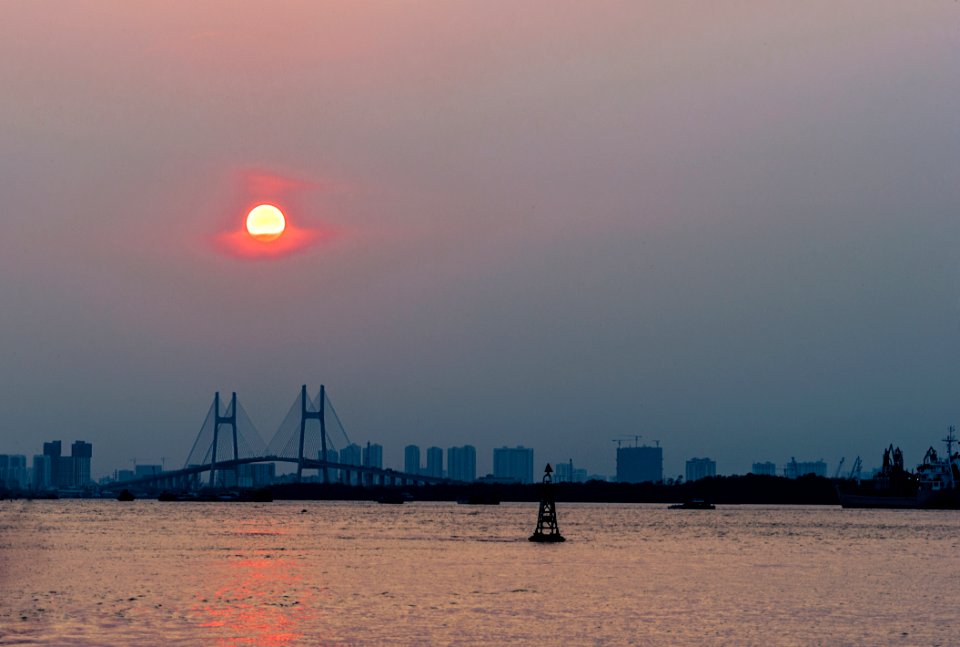 Ship Near Brown Bridge Across Sea During Sunset photo