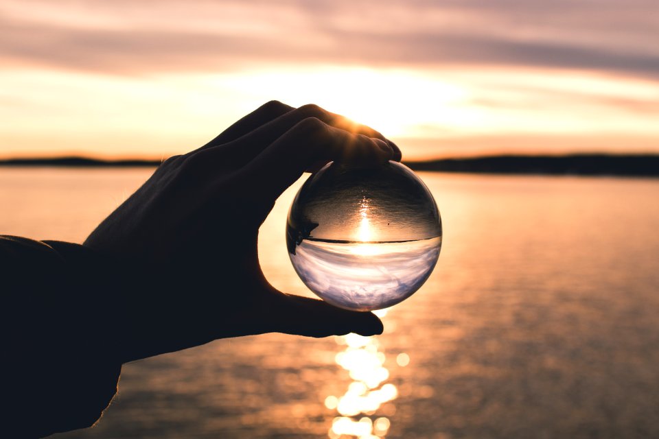 Photo Displays Person Holding Ball With Reflection Of Horizon