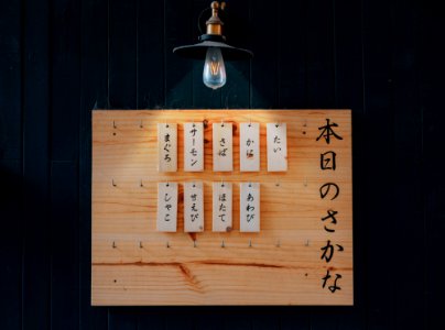 Kanji Printed Tags Hanged On Brown Wooden Board Lighted By Pendant Lamp photo