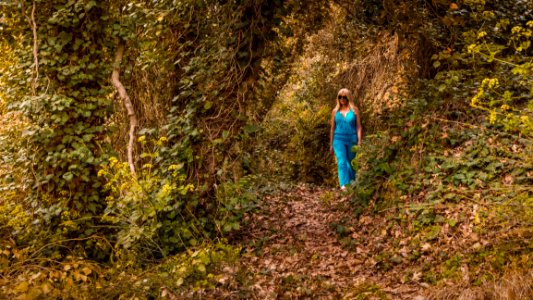 Woman Wearing Blue Jumpsuit Walking In Forest photo
