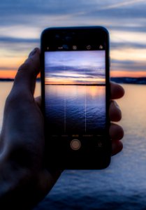Person Holding Post-2014 Iphone Taking A Photo Of Body Of Water