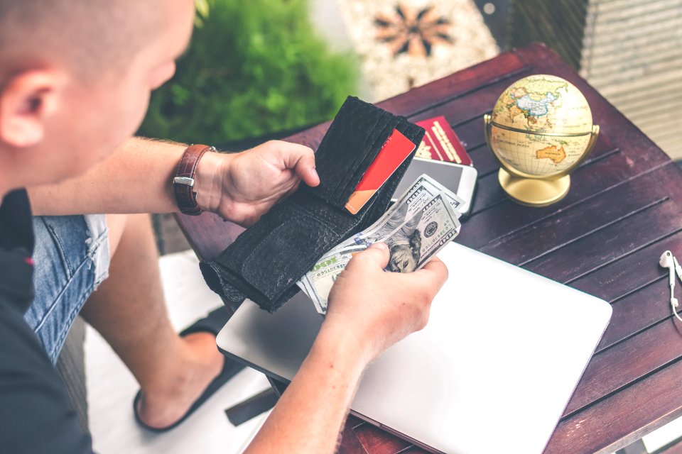 Man Holding Us Dollar Banknotes And Black Leather Bi-fold Wallet