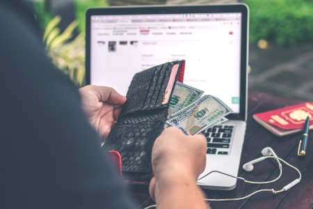 Person Holding 10 Us Dollar Banknote In Front Of Gray And Black Laptop Computer photo