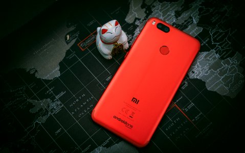 Red Xiaomi Mi Smartphone Beside White Cat Figurine photo