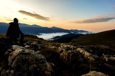 Person In Black Hoodie Sitting On Gray Stone photo