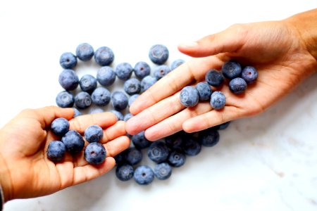 Two Persons Hand With Blueberries On Top