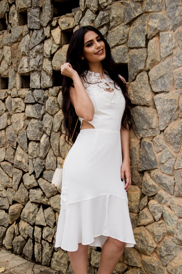 Woman In White Dress Leaning On Brick Wall Posing For Photo