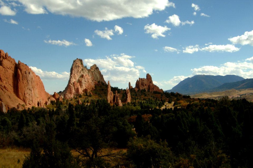 Brown Rock Formation Near Green Trees Under Cloudy Sky