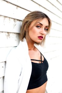 Woman Wearing Black Crop Top Leaning Against White Wall photo