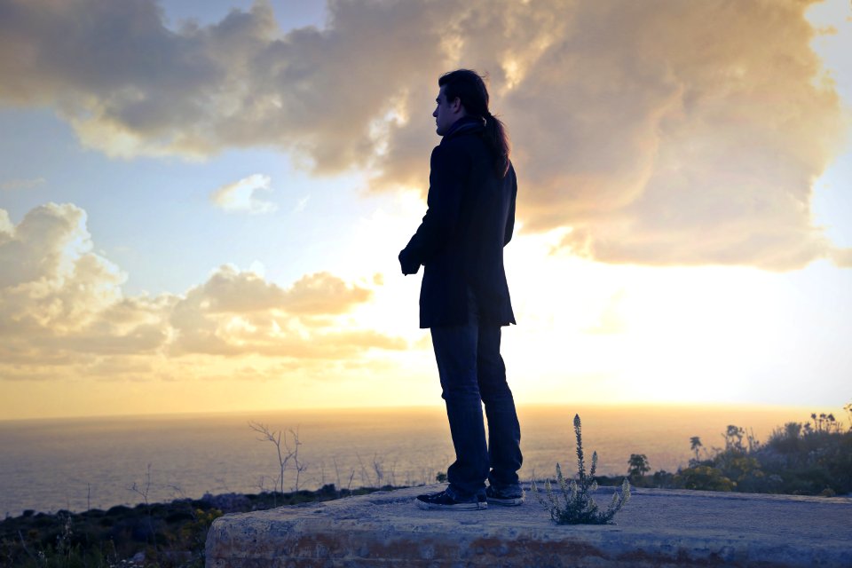 Man Wearing Black Coat Standing Near Sea During Golden Hour