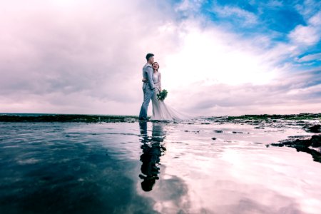 Man In Gray Dress Suit Jacket Embraces Woman Wearing Wedding Gown photo