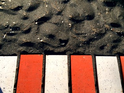Red And White Metal Planks On Black Sand photo