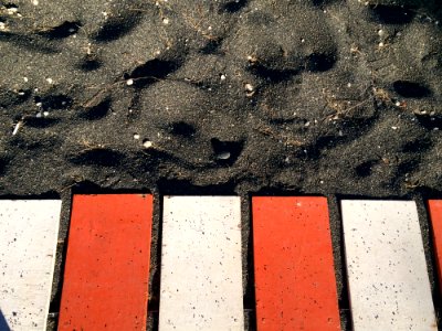 Red And White Metal Planks On Black Sand