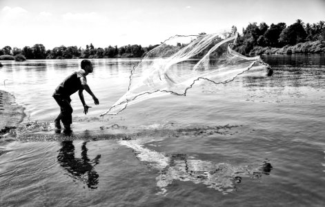 Grayscale Photo Of Man Throwing A Fishing Net photo