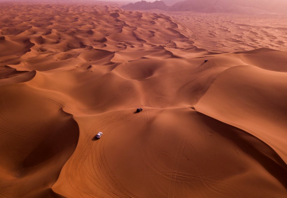 Two Vehicles On Desert Dunes