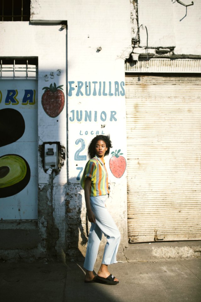 Woman In Yellow Mid-sleeved Shirt Standing Beside White Wall photo