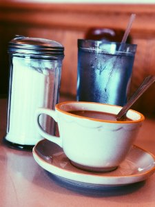White Ceramic Mug Fill With Coffee Beside Condiment Shaker photo