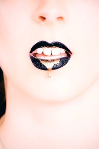 Woman Wearing Black Lipstick With Gold Dripping Out photo