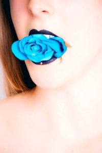 Woman With Black Lipstick Biting Blue Rose photo