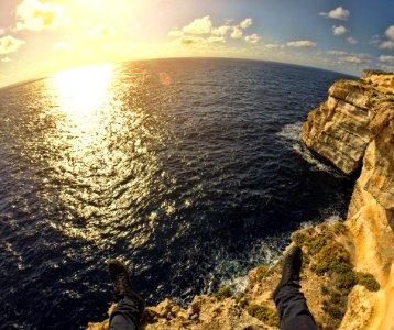 Person On Top Of Stone Island In Front Of Sea During Sunset photo