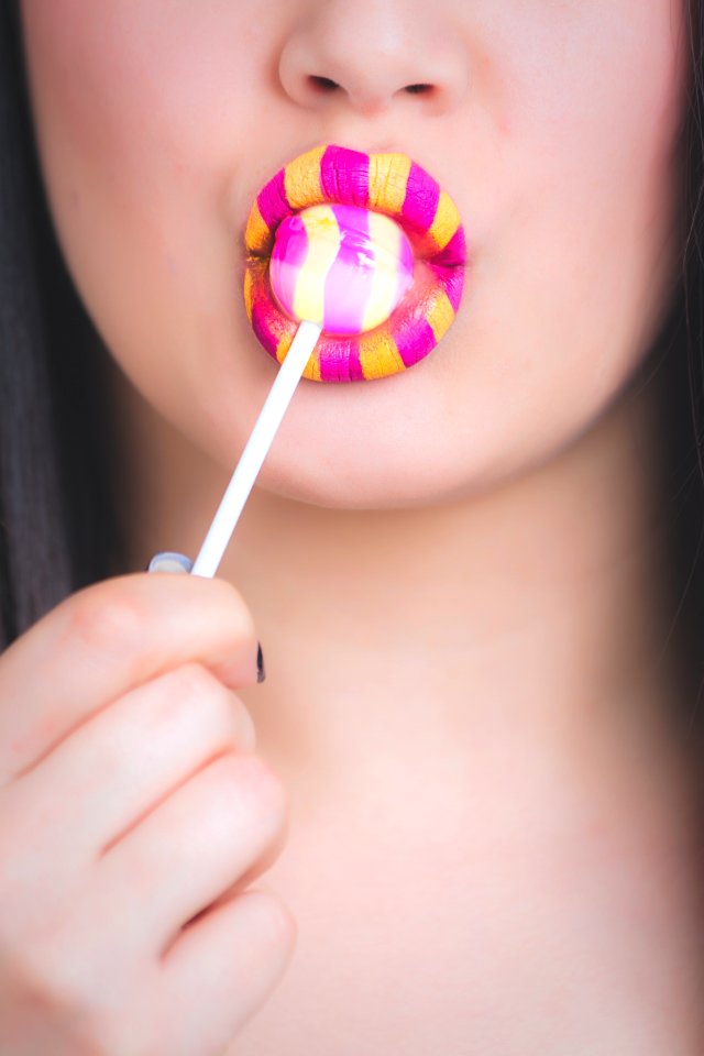 Woman With Yellow And Pink Lipstick Eating LolliPop