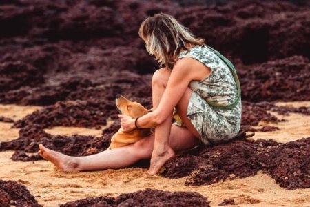 Woman With Green Floral Sleeveless Mini Dress Sitting On Brown Sand Close-up Photography photo