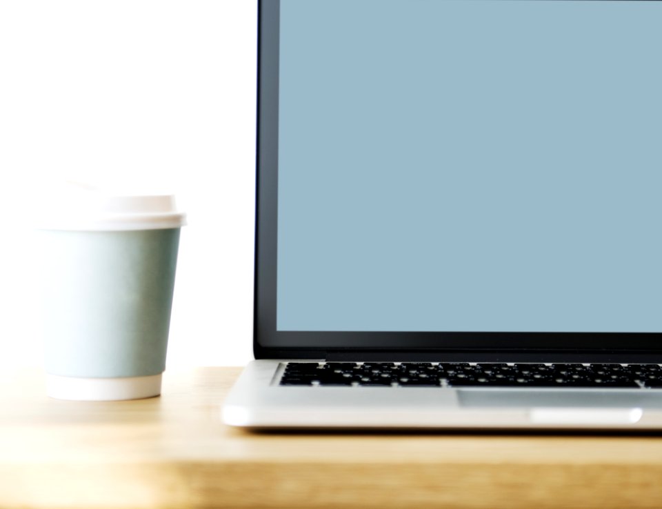 Macbook Pro Beside Gray Disposable Cup On Brown Wooden Surface
