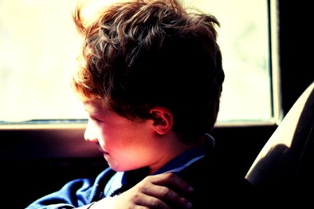 Boy In Blue Jacket Sitting Next To Vehicle Window