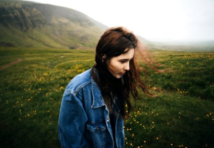 Woman Wearing Blue Denim Jacket Walking On The Green Grass Field photo