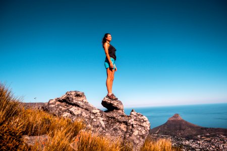 Woman In Black Top And Blue Shorts On Stone Under Blue Sky photo