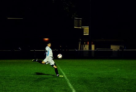Person Kicks Soccer Ball In Field photo