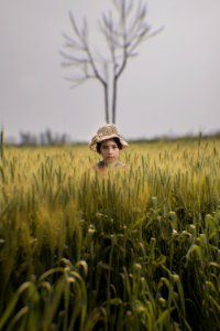 Toddler Wearing Brown Hat In The Middle Of Green Field photo