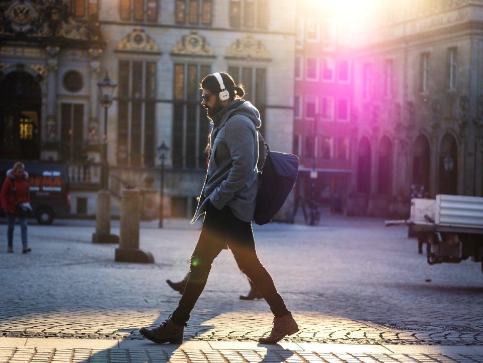 Man In Gray Hooded Jacket Walking On Gray Bricks Pavement