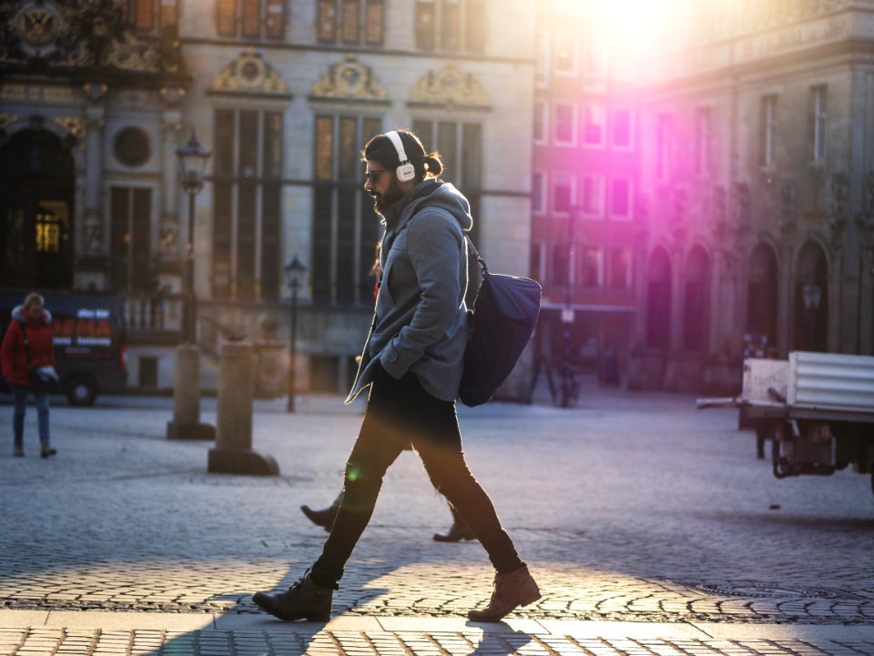 Man In Gray Hooded Jacket Walking On Gray Bricks Pavement photo