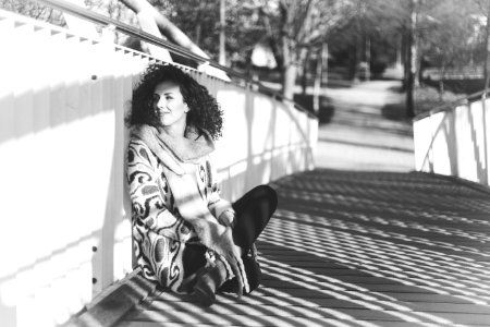 Grayscale Photo Of A Woman Sitting Beside A Rail photo