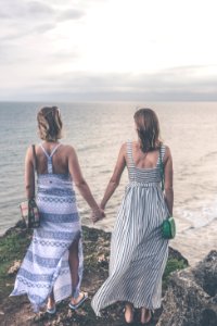 Two Women Wearing Sleeveless Dress Holding Each Others Hand On Cliff photo