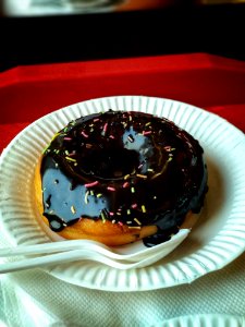 Chocolate Donut Above Round Paper Plate And Plastic Spoon And Fork