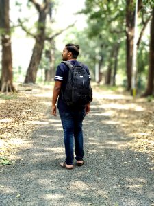 Man In Black And White T-shirt And Blue Denim Jeans Carrying Backpack photo