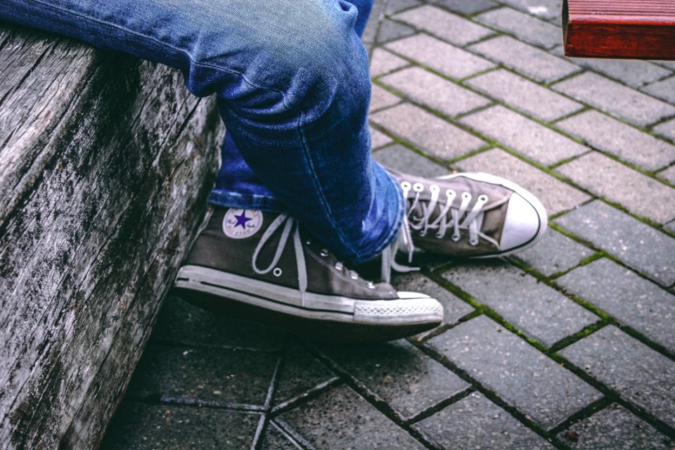 Person Wearing Brown Converse All-star High-top Sneakers And Blue Denim Jeans While Sitting On Bench photo