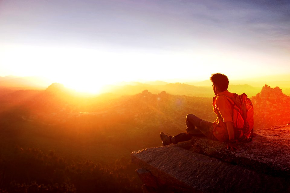 Man Sitting On Edge Facing Sunset