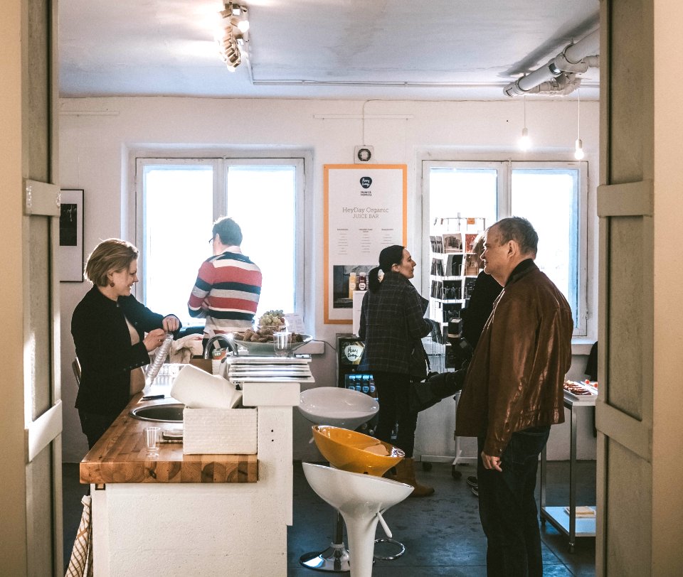 Man Wearing Brown Leather Jacket Standing In Front Of Desk With Woman Wearing Black Cardigan