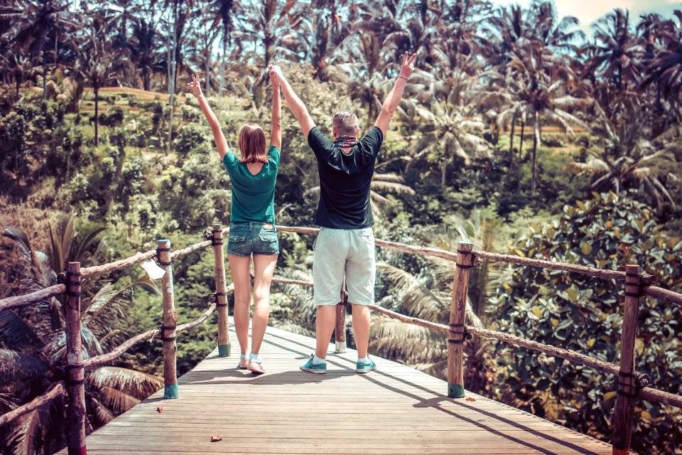 Man Wearing Black Shirt Beside A Woman In Green Shirt Raising Their Hands In The Air
