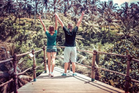 Man Wearing Black Shirt Beside A Woman In Green Shirt Raising Their Hands In The Air photo