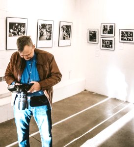 Man In Brown Jacket Blue Denim Jeans And Blue Dress Shirt Holding Dslr Camera photo