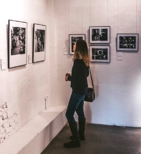 Woman Wearing Black Sweater And Blue Denim Jeans Staring At Paintings Inside Well-lit Room