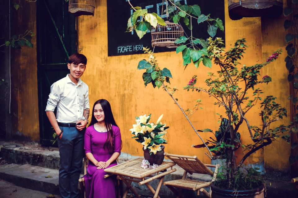 Sitting Woman Wearing Purple Elbow-sleeved Dress And Standing Man Wearing White Dress Shirt