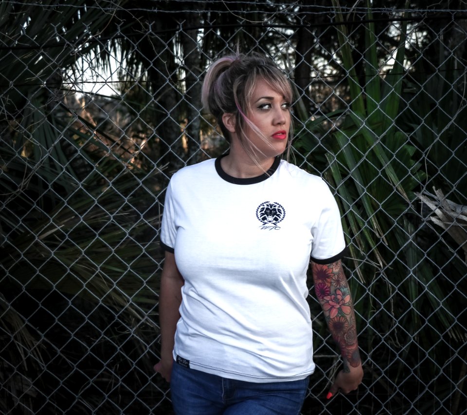 Woman Wearing White Crew-neck T-shirt With Black Trim And Blue Denim Bottoms Beside Wire Fence