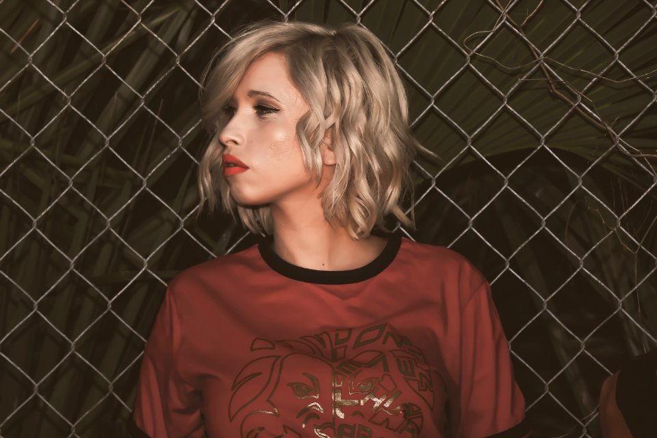 Close-Up Photography Of A Woman Leaning On Chain Link Fence