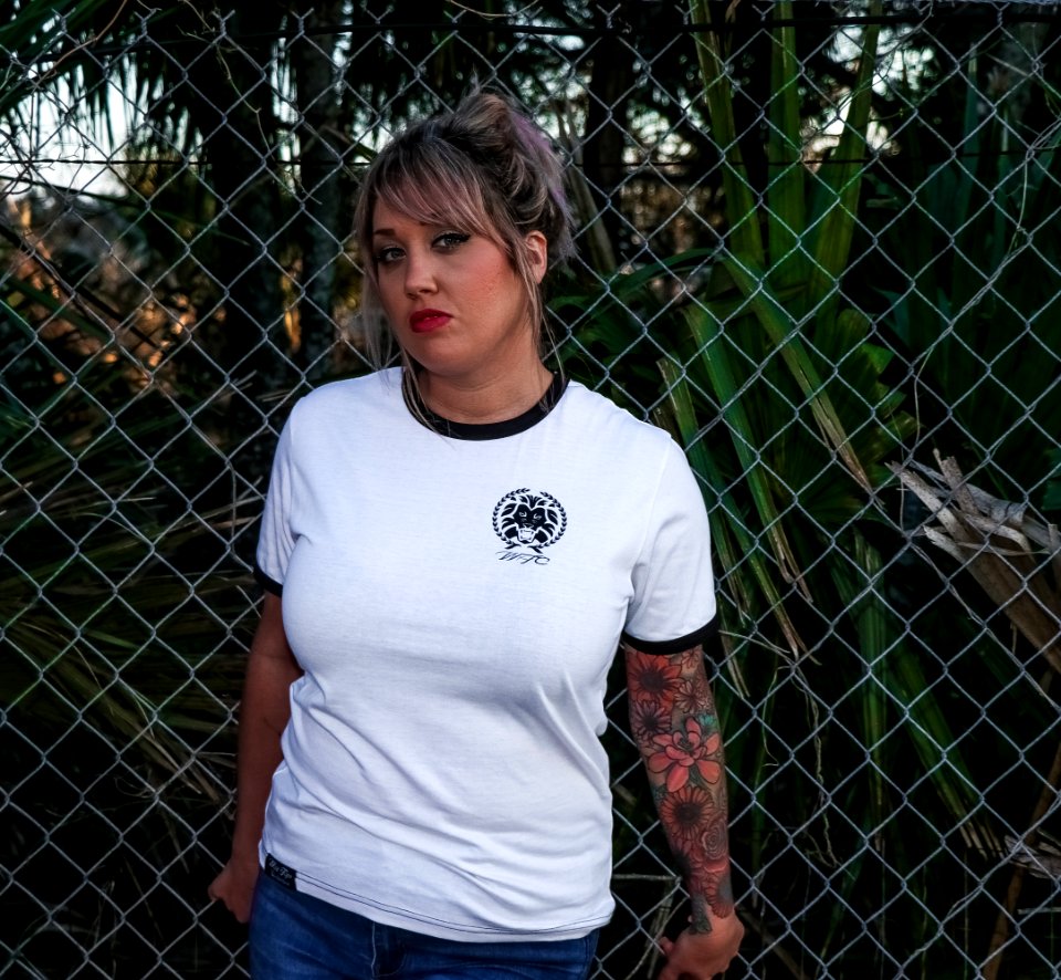 Female Wearing Black And White Crew-neck T-shirt And Blue Denim Bottoms Leaning On Chicken Wire