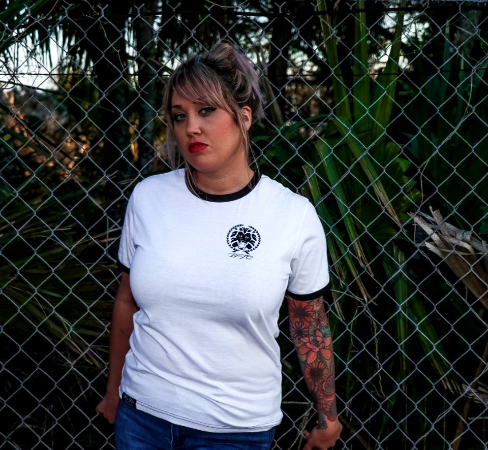 Female Wearing Black And White Crew-neck T-shirt And Blue Denim Bottoms Leaning On Chicken Wire photo